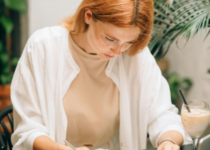 Een vrouw werkt geconcentreerd aan een bureau met documenten en een laptop.